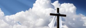 Photograph of a cross on a hill with clouds behind
